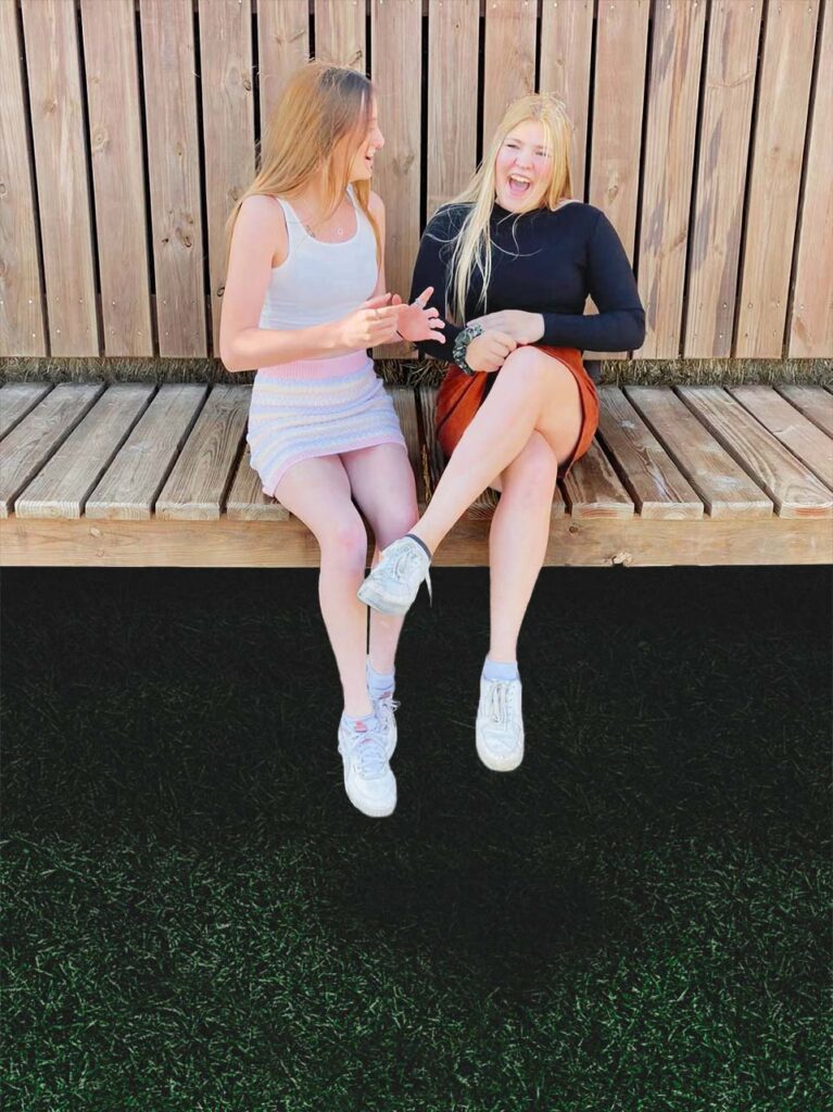 Two happy girls on a bench.